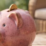 Pink piggy bank with a coin inserted, representing saving for future healthcare expenses.